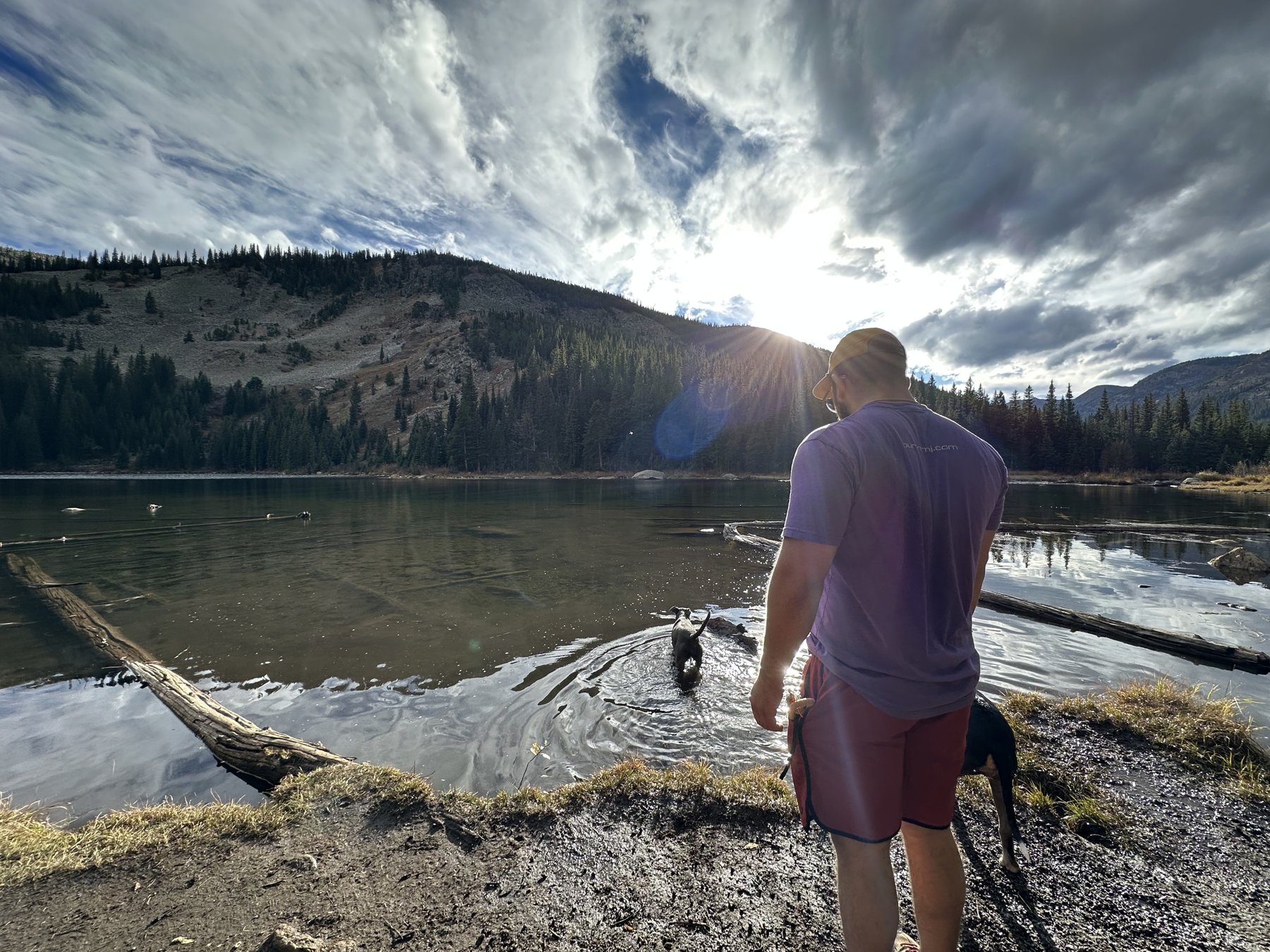 A man and his dog at a mountain lake in the afternoon sun