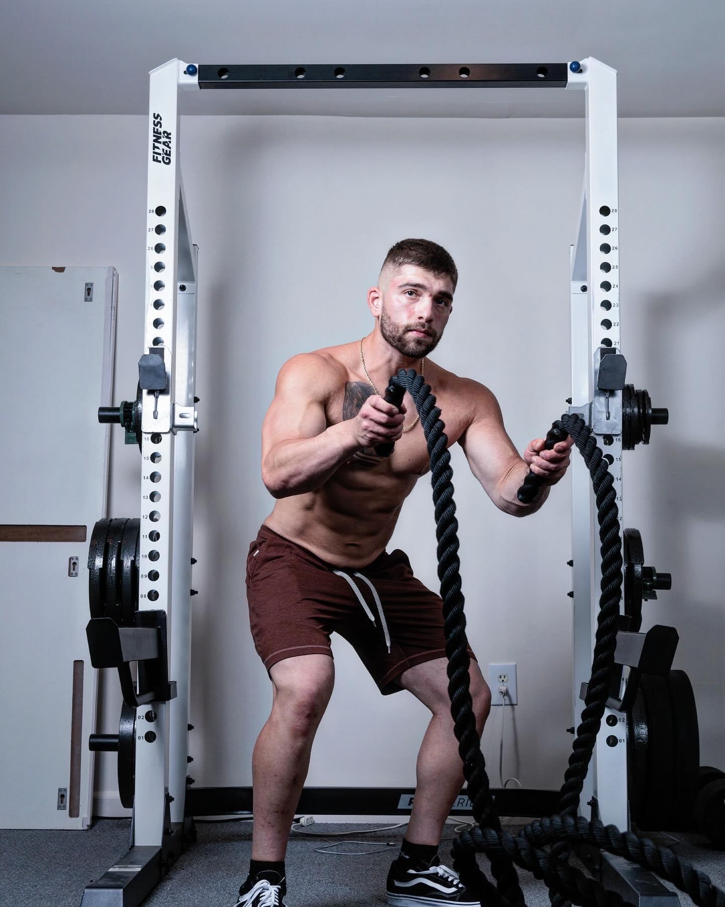 Jeffrey Heckendorn training with battle ropes in front of a squat rack
